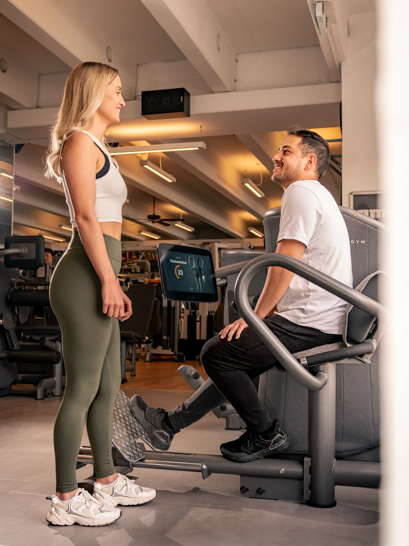 Trainer begleitet ein Mitglied beim Kennenlernen der smarten Trainingsgeräte